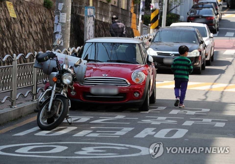 ▲ 민식이법 시행 첫날인 25일 한 초등학교에 불법 주차된 차량 옆으로 한 어린이가 보행 하고 있다. (사진=연합뉴스)