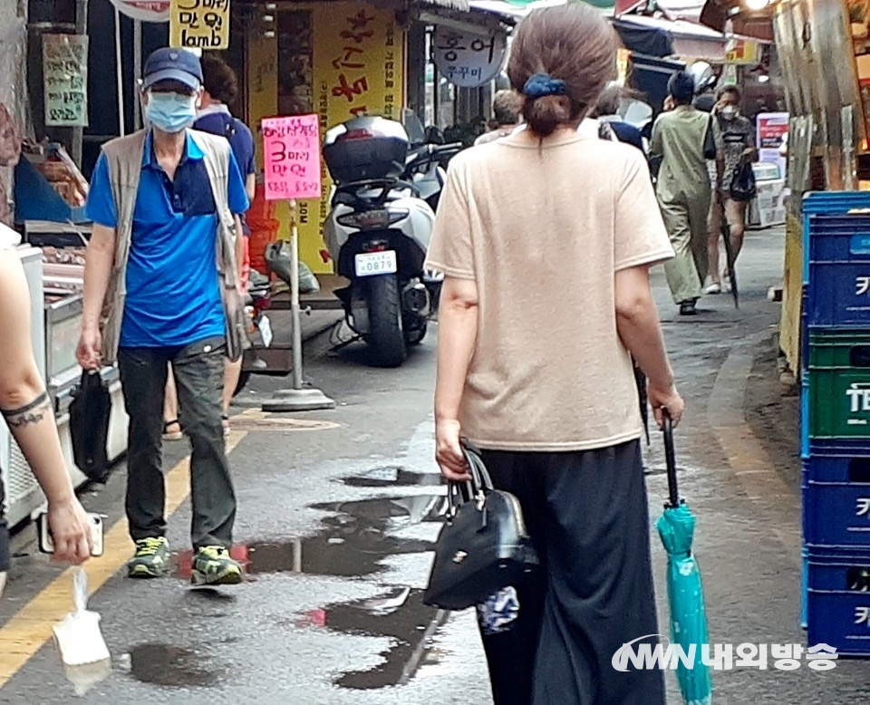 ▲ 골목시장에 있는 두부 가게에서 한 주부가 두부 등을 구매하고 있다. 한 20대 여성이 두부 한모를 사서 골목을 걸어가고 있다. (사진=내외방송 정수남 기자)