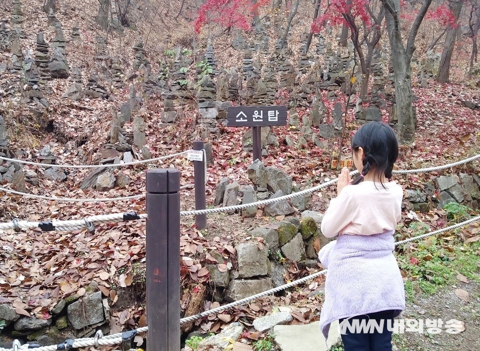 ▲ 은행동에서 남문을 가다보면 약사사 입구와 이곳에서 500여m 떨어진 곳에는 통일기원탑이, 다시 이곳에서 10여m 떨어진 백련사 인근에는 소원탑이 각각 자리하고 있다. 한 초등학생이 소원탑 앞에서 소원을 빌고 있다. (사진=내외방송 정수남 기자)